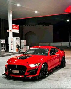 a red sports car parked in front of a gas station