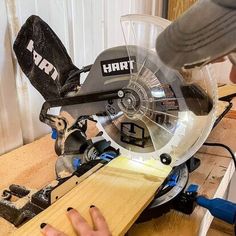 a person using a circular saw to cut a piece of wood with a mitt