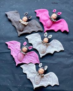 four little bats are laying on the ground with pink and gray ones in their hands