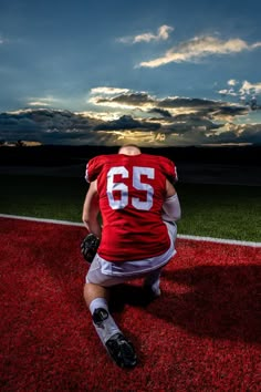 a man sitting on top of a field wearing a red jersey