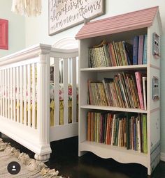 a baby crib next to a book shelf with books on it and a sign above the crib