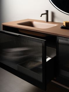 a bathroom sink sitting under a mirror next to a wooden cabinet with an oval mirror above it