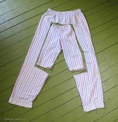 a pair of pink and white striped pants laying on top of a wooden floor next to a green wall