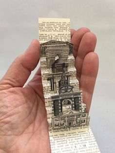 a person holding up a piece of paper with an image of a clock tower on it