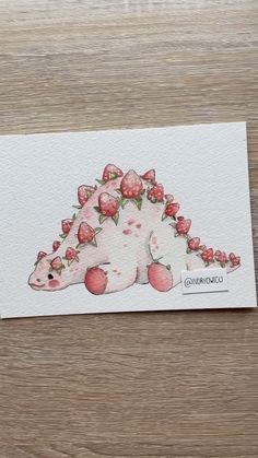 an animal with strawberries on it's back sitting on a wooden table next to a piece of paper