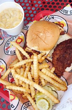 a chicken sandwich, fries and pickles on a tray at a fast food restaurant