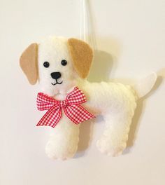 a white stuffed dog with a red checkered bow hanging from a hook on a wall