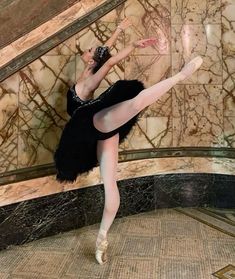 a ballerina is posing in front of a marble wall