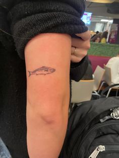 a person with a small fish tattoo on their arm