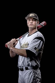 a baseball player is holding a bat and posing for a photo with his uniform on