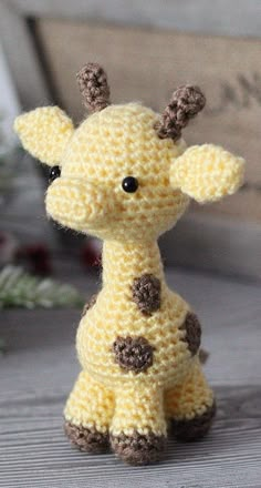 a small crocheted giraffe sitting on top of a wooden table