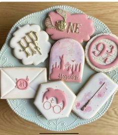 some cookies are on a plate with pink and white icing in the shape of envelopes