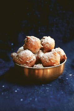 powdered sugar covered donuts in a gold bowl