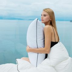 a woman sitting on top of a bed holding a pillow