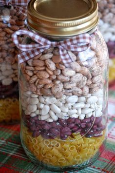 a jar filled with lots of different types of beans and cereals on top of a table