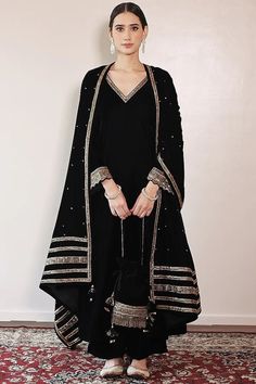 Black Embroidered A-Line Kurta Set Featuring a black A-line kurta in silk velvet base with side pockets and lace hand embroidery. It is paired with matching palazzo pants and a velvet shawl. This product will be shipped to you after 1-2 weeks from the date of order placed. All custom made orders are not returnable. Pls contact for Size chart and for other more colors Request You :To provide contact details for courier services. {VARIATION MAY COME DEPENDING UPON AVALIBILITY OF LACES OR GOTTA PATI} NOTE:  1) Visual Samples on website may differ slightly from actual product due to light & effects during photography (Length & Breadth have 1 n 1.5 inches +/-). 2) Before placing order ,pls confirm product n color availability on +91 7903893945 & +91 8447750028(WhatsApp) 3) For Wholesale Order M Velvet Sharara, Black Velvet Suit, Velvet Suit Design, Suits For Women Indian, Velvet Kurta, Velvet Dress Designs, Independance Day, Velvet Shawl, A Line Kurta