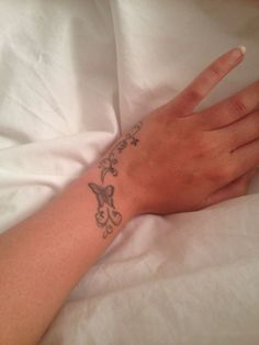 a woman's hand with a butterfly tattoo on her left wrist and the other arm