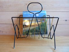 a magazine rack with two magazines in it on top of a wooden table next to a wood wall