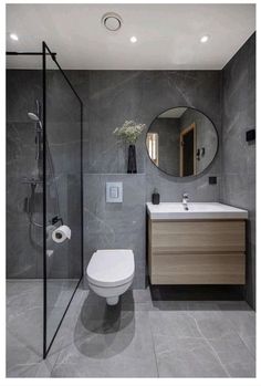 a bathroom with a toilet, sink and shower stall in grey marbled finish to the walls