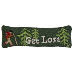 a green pillow with the words get lost on it and a man walking in front of trees