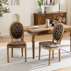 a dining room table with two chairs and a wine glass on the table in front of it