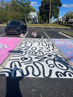 a person kneeling down on the side of a road next to some chalk drawings and trees