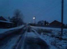 a snowy road with street lights in the distance