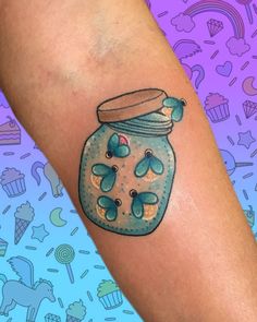 a person with a tattoo on their arm has a jar filled with flowers and butterflies