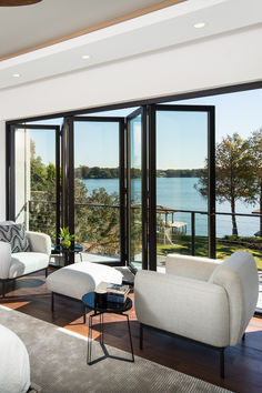 a living room filled with furniture next to a large glass door leading to a lake