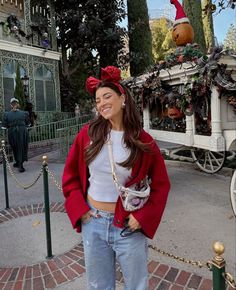 a woman standing in front of a horse drawn carriage wearing a red hat and bow tie