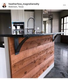 a kitchen with an island made out of wood and black granite counter tops, along with a stainless steel faucet mounted on the wall