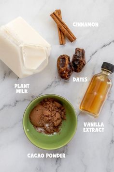 ingredients to make chocolate fudges on a marble counter top with cinnamon, dates, cocoa powder and milk