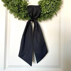 a wreath with a black bow hanging on the front door