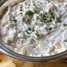 a metal bowl filled with white dip surrounded by chips