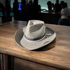 The Rough Cut is a cowboy hat like you've never seen before. Classic at first sight- but with plenty of modern twists. Just the color scheme is much more modern and urban than the classic brown or beige cowboy hats of yesteryear. Featuring a vintage style binding on the underside of the brim. Yet, structured with a K. Doughty signature "diamond cut crown". Decorated with a nice black grosgrain ribbon and bow and a winged dog pin. Lined with white satin featuring red/white parlor logo. Tall and Wide for the bold. Size 59cm : 7 3/8 Gray Western Hats For Rodeo, Gray Western Hat With Short Brim, Western Style Wide Brim Gray Hat, Adjustable Western Gray Hat Band, Gray Western Fedora Hat, Adjustable Gray Western Hat Band, Adjustable Gray Hat For Rodeo, Felt Cowboy Hat, Felt Cowboy Hats