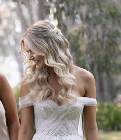 a woman in a white dress is walking with another woman holding her hand out to her side