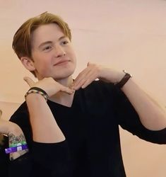 a young man is posing for the camera with his hand on his chin and wearing a watch