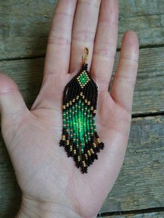 a hand holding a small beaded hamsa hanging from it's palm