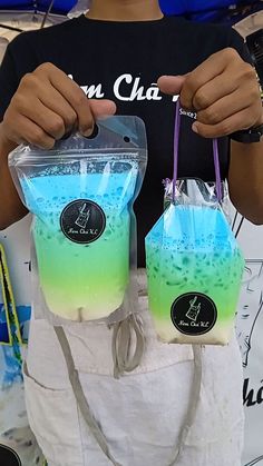 a person holding two bags filled with blue and green liquid