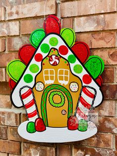 a gingerbread house ornament hanging on a brick wall with candy canes