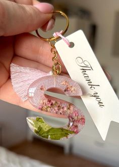 a person holding a keychain with flowers on it and a name tag attached to it