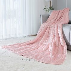 a living room with a couch, rug and pink blanket on top of the sofa