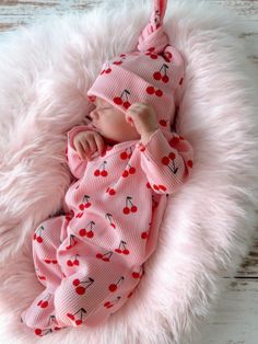 a baby is sleeping in a pink blanket with cherries on it's head