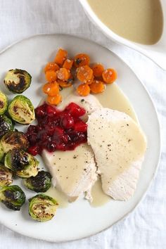 a white plate topped with chicken, brussel sprouts and cranberry sauce