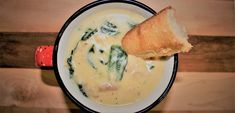 a bowl filled with soup next to a piece of bread on top of a wooden table