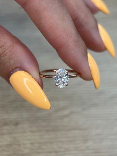 a woman's hand with yellow nails and a ring on her finger, holding a diamond