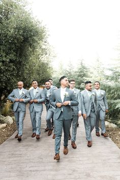 a group of men in grey suits walking down a path together with their arms around each other