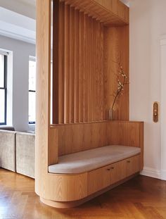 a wooden bench sitting on top of a hard wood floor next to a white wall