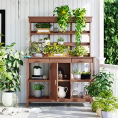 a wooden shelf filled with potted plants on top of a porch