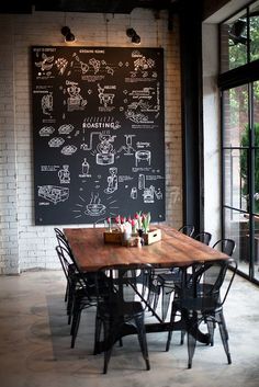 a dining room table with chairs and a chalkboard on the wall behind it that has writing all over it